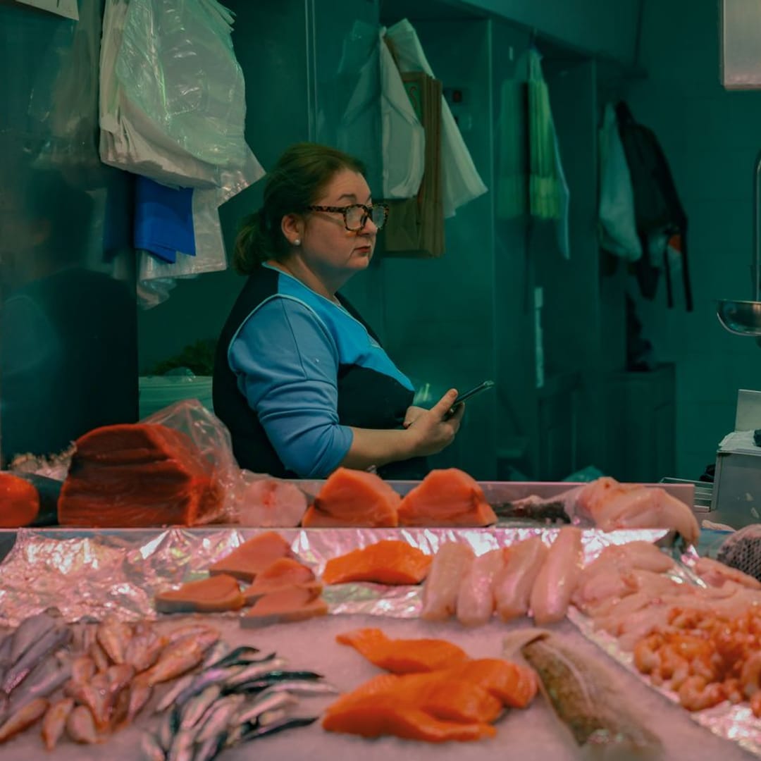La pescadera atiende tras el mostrador del puesto de pescado