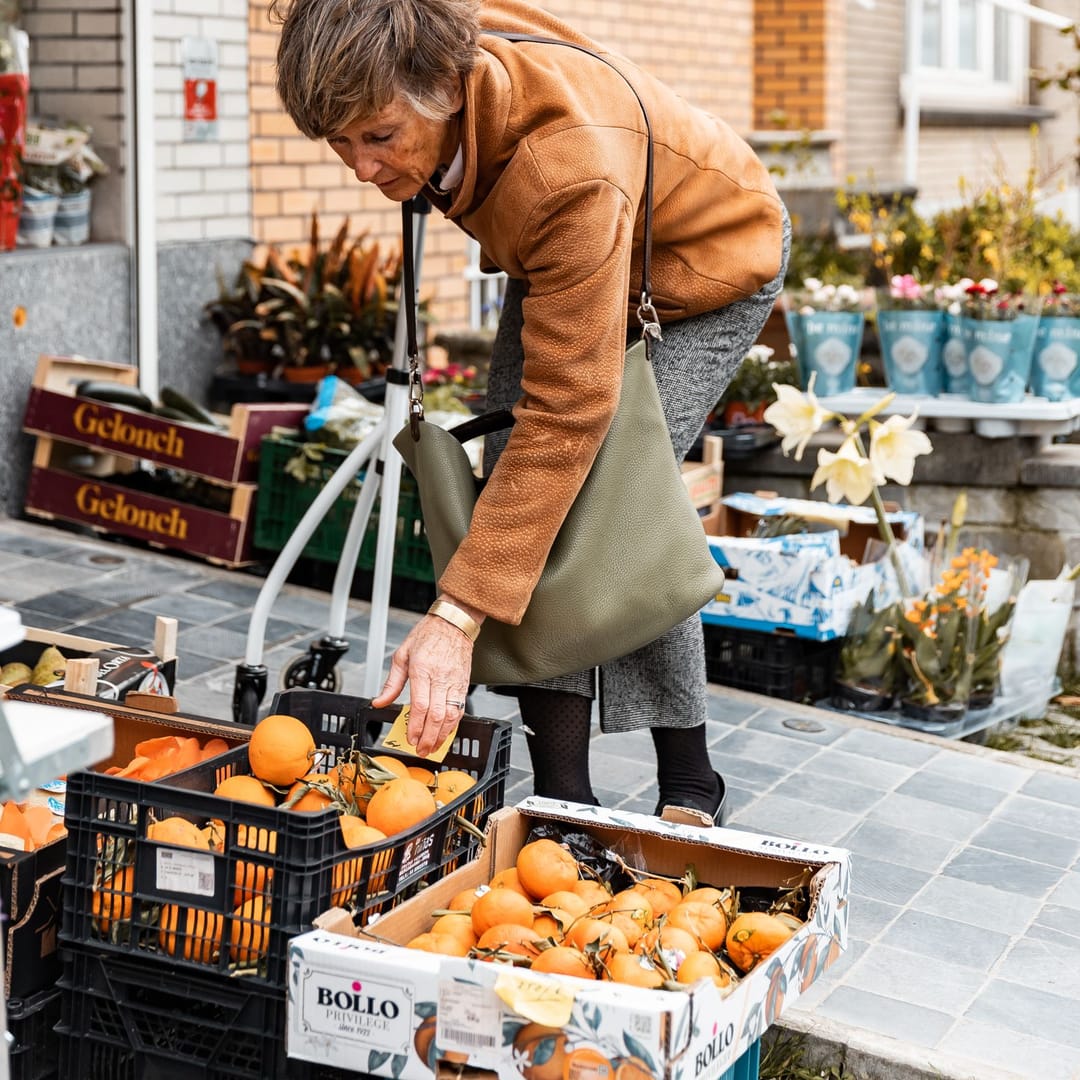 Una señora elige naranjas de las cajas del puesto